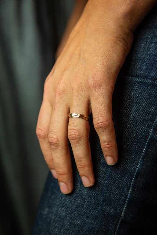 closeup of a hand resting on a leg with two gold rings on their ring finger.