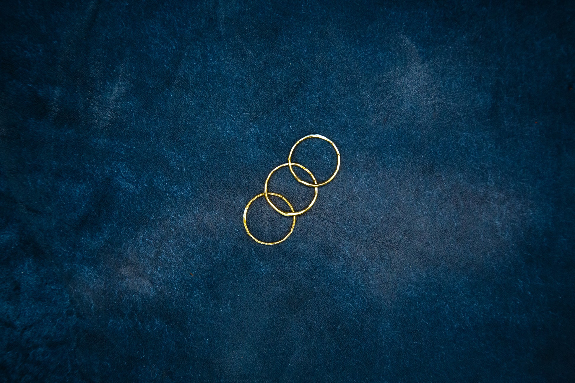 A closeup of three gold rings on blue leather.