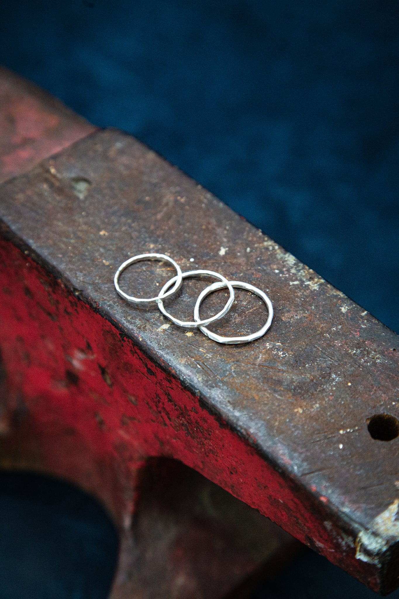 Three silver rings on top of a red anvil.