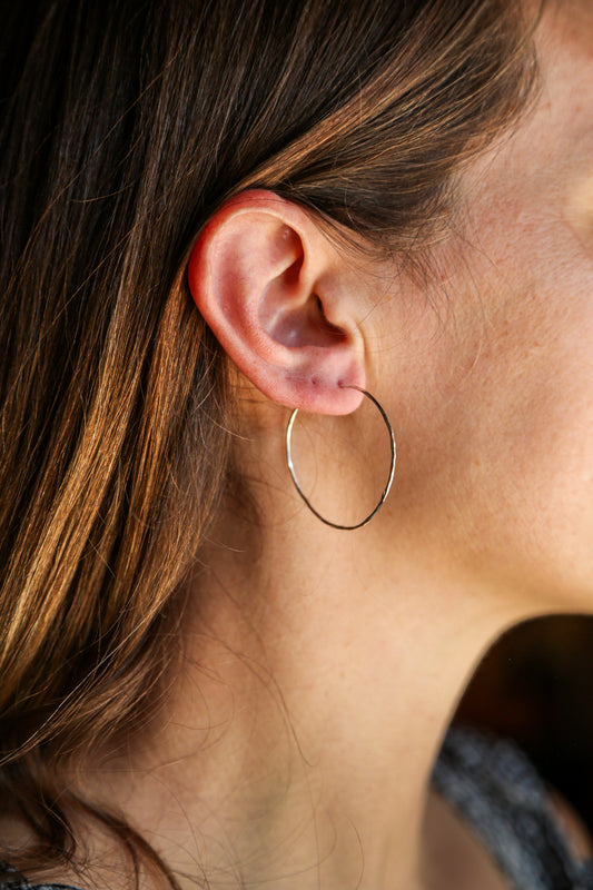 A women wearing a silver hoop earing.